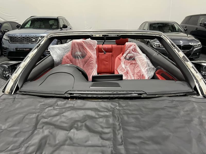 The bare windscreen aperture of a BMW M4 convertible with the bonded edge exposed and the interior wrapped
