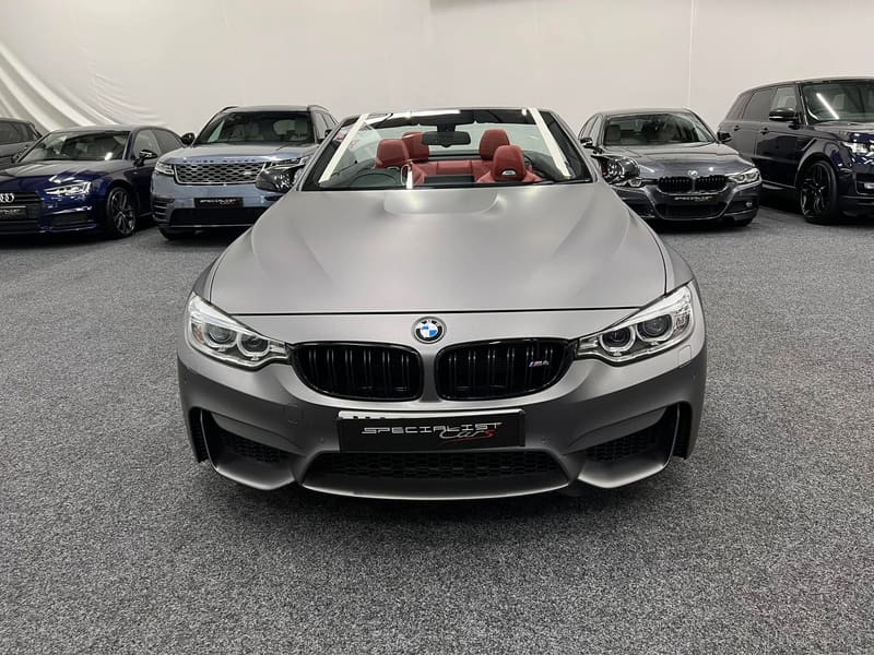 A matte grey BMW M4 convertible photographed head on with its new windscreen fitted and the roof down