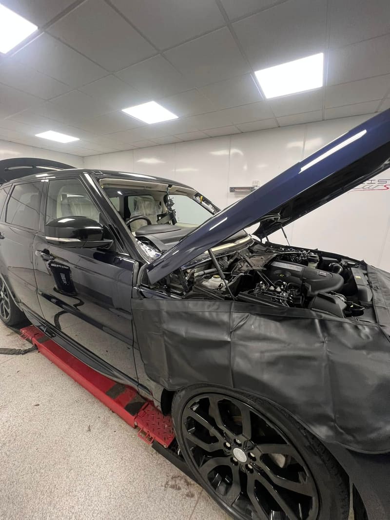 A Range Rover Sport prepared for windscreen work with the bonnet up and covers over both wings
